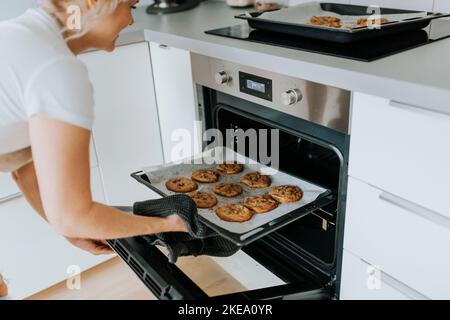 Femme prenant des biscuits hors du four Banque D'Images