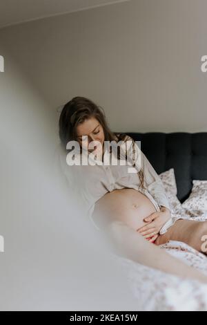 Pregnant woman sitting in bed Banque D'Images