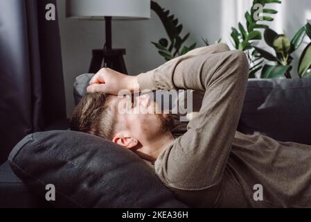 Dépression, concept d'apathie. Fatigué frustré caucasien 30s couché sur le canapé à la maison, pensant aux problèmes, sensation de stress, fatigue, touchant la tête, Banque D'Images