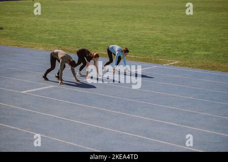 Deux filles et un garçon se préparent pour la course à pied 100m Banque D'Images