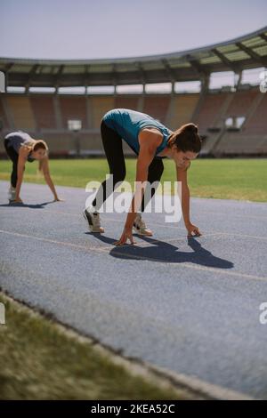 Deux magnifiques filles se sont frapune sur une piste de sport bleue au stade Banque D'Images