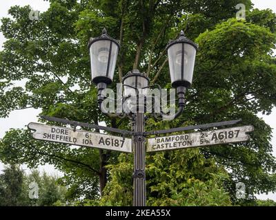 Borne métallique à l'ancienne avec trois luminaires intégrant également des panneaux routiers pour fingerpost, Hathersage, Derbyshire, Royaume-Uni Banque D'Images