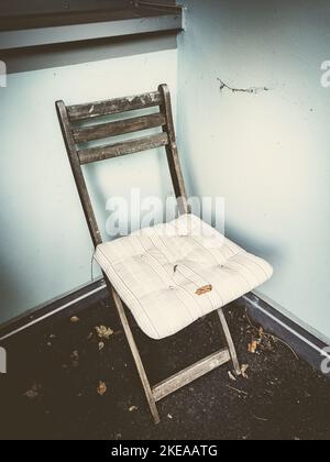 Ancienne chaise pliante dans le coin d'une maison Banque D'Images