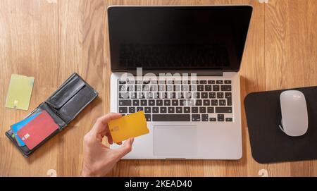 Main d'achat en ligne avec cartes de crédit, portefeuille et dessus d'ordinateur portable Banque D'Images
