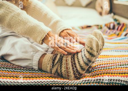Gros plan de la femme faisant des exercices d'étirement sur le lit portant des chaussettes chaudes en laine d'hiver colorées. Concept de personnes saines de style de vie. Exercices pour ag Banque D'Images