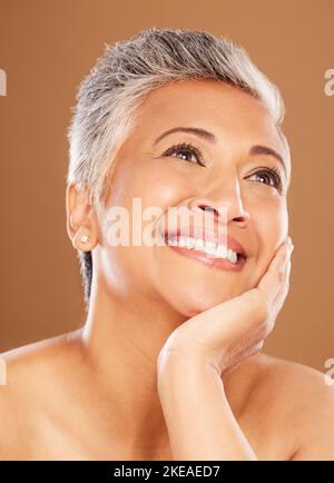 Visage, beauté et réflexion avec une femme senior en studio sur fond marron pour le bien-être ou les soins naturels de la peau. Idée, cosmétiques ou soins de la peau avec un Banque D'Images