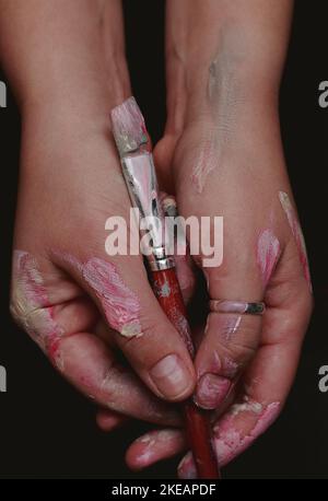 gros plan des mains d'un artiste avec une brosse en couleur Banque D'Images