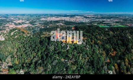 Vue aérienne par drone du Palais Pena, un château romantique dans les montagnes de Sintra au Portugal 25km à l'ouest de Lisbonne avec campagne environnante avec l'océan Banque D'Images