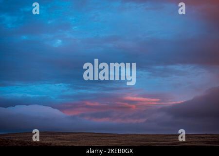 Les derniers rayons du soleil de l'après-midi éclairant les nuages dans un ciel froid et sombre au-dessus d'un paysage de Roggeveld. Près de Sutherland. Cap du Nord. Afrique du Sud. Banque D'Images