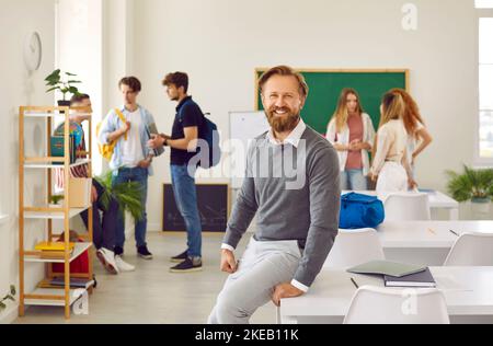 Portrait d'un homme joyeux qui travaille comme enseignant d'école debout dans la salle de classe Banque D'Images