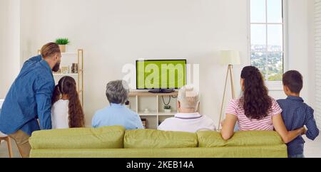 Les grandes familles de plusieurs générations applaudissent tout en regardant un match de football à la télévision à la maison. Banque D'Images