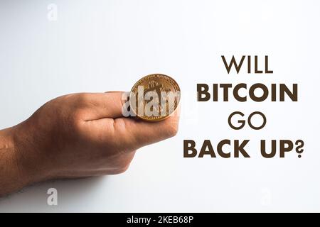 Will bitcoin aller de retour - gros plan d'une main jetant une monnaie de bitcoin d'or Banque D'Images