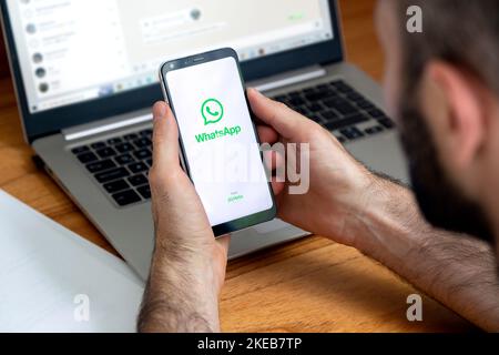 Logo de l'application WhatsApp sur l'écran du téléphone entre les mains d'un homme. Smartphone avec écran blanc et logo vert. Banque D'Images