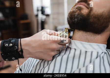 vue partielle de barber taille du cou de l'homme barbu avec tondeuse cheveux dans barbershop, image de stock Banque D'Images