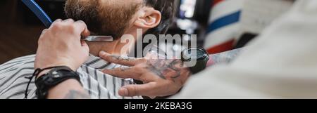 vue rognée d'un barbier flou rasage homme barbu avec rasoir droit, bannière, image de stock Banque D'Images