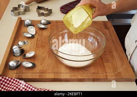 Préparation de biscuits de Noël faits maison - verser le sucre dans un bol en verre sur une table Banque D'Images