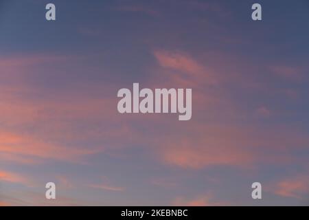 Coucher de soleil ou ciel de lever de soleil avec des rayons de lumière éclairant le bleu foncé et des nuages roses et orange clairs et doux. Banque D'Images