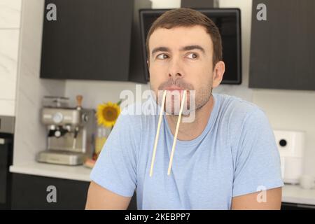 Homme faisant le visage drôle avec une paire de baguettes Banque D'Images