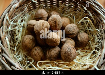 Noix en coquille éparpillées sur Un copeaux de bois à l'intérieur D'Un pot en osier fait maison Banque D'Images