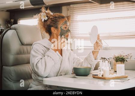 Une femme utilisant la crème de beauté sur le visage pour arrêter le vieillissement et éliminer les rides. Les femmes utilisent des produits naturels sur sa peau à l'intérieur d'une camionnette de camping-car dans un mode de vie hors réseau à la maison seul Banque D'Images