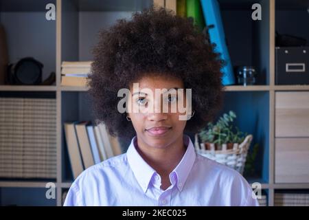 Portrait en gros plan d'une jeune femme à la peau sombre et élégante, avec une coiffure afro mauriquement. Femme d'affaires afro-américaine sur le lieu de travail de bureau. Jeune femme confiante regardant l'appareil photo Banque D'Images
