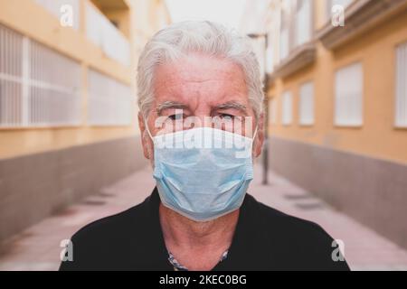 une personne âgée ou mature triste et contrariée qui regarde l'appareil photo porte un masque pour prévenir le covid-19 ou le coronavirus - stayathome en quarantaine et verrouillage - regardant le appareil photo Banque D'Images