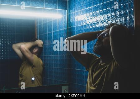 gros plan portrait d'homme triste et déprimé bouleversé dans la salle de bains devant le miroir Banque D'Images