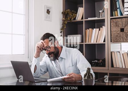 Malsain vieux stressé homme d'affaires regardant l'ordinateur portable, utilisant l'ordinateur, souffrant de trop de travail ou de long travail excessif d'ordinateur. Banque D'Images