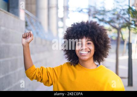 Concept de la vie noire. Une jeune femme africaine ou américaine sérieuse avec son bras vers le haut avec la main de près regardant la caméra. Banque D'Images