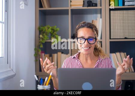 Doute incertain heureuse femme caucasienne incapable de prendre la décision à partir des choix disponibles sur son écran d'ordinateur portable. Femme d'affaires souriante discutant vidéo ou participant à une conférence en ligne au bureau Banque D'Images