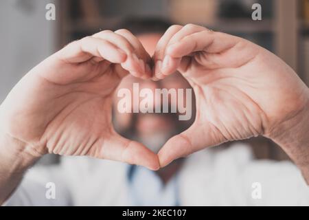 Homme faisant le geste de forme de coeur avec les mains. Main d'un médecin masculin faisant un symbole d'amour. Professionnel de la santé exprimant l'amour et le soutien aux patients. Soignant médical faisant la promotion d'un don de charité Banque D'Images