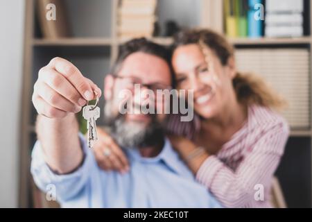 Couple heureux montrant les clés de leur nouvelle maison ou bureau. Portrait de femme souriante avec mari tenant la clé de leur nouvel appartement. Deux locataires ou locataires déménageant ou se déplaçant avec les clés à la main Banque D'Images