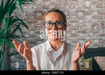 Portrait d'une jeune femme souriante en lunettes regardant l'appareil photo devant un mur de briques. Une femme de race blanche est heureuse de donner un cours de formation pédagogique ou de faire un appel de vidéo conférence Banque D'Images