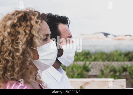 gros plan et portrait de deux personnes regardant loin portant un masque médical et chirurgical ne préviennent pas covid-19 ou tout type de nouveau virus - femme avec le masque sur son visage et homme à côté d'elle - pademic style de vie Banque D'Images