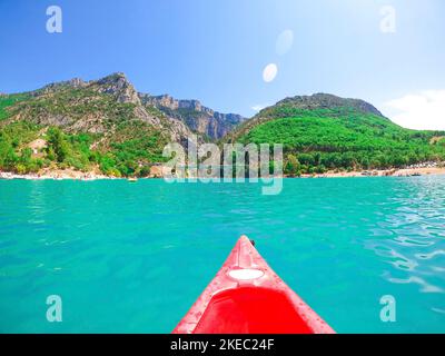 Arc de canoë rouge sur la mer turquoise avec les montagnes en arrière-plan contre le ciel. Paysage marin pittoresque avec montagne sur la côte contre le ciel bleu lors d'une journée ensoleillée. Kayak rouge au premier plan Banque D'Images