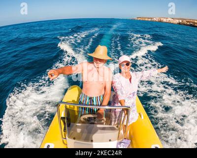 couple de deux personnes âgées et matures ayant du plaisir et appréciant ensemble leurs vacances avec un bateau de location de dériveur au milieu de la mer ou de l'océan - heureux aînés conduisant un petit bateau souriant Banque D'Images