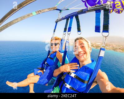 gros plan et selfie de deux heureux ensemble en volant avec un cerf-volant au milieu de la mer ayant amusement - couple d'adultes appréciant l'été Banque D'Images