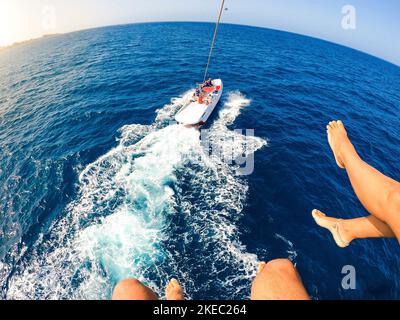 gros plan et portrait des jambes de deux personnes vollent dans les airs pendant qu'un bateau les tire - adultes s'amusant ensemble en été faisant parapente et appréciant leurs vacances Banque D'Images