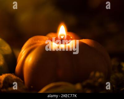 Bougie en forme de citrouille dans un cadre sombre. Le feu brille et dégage une atmosphère chaleureuse. Belle décoration d'automne dans la chambre. Gros plan d'une bougie. Banque D'Images