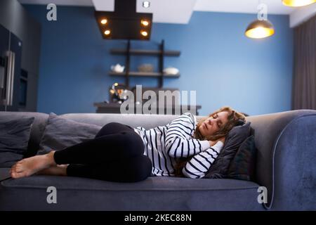 Une fille dort sur un canapé confortable dans la salle de séjour à l'heure de la sieste. Femme dormant prenant la sieste sur le canapé pendant la journée. Banque D'Images