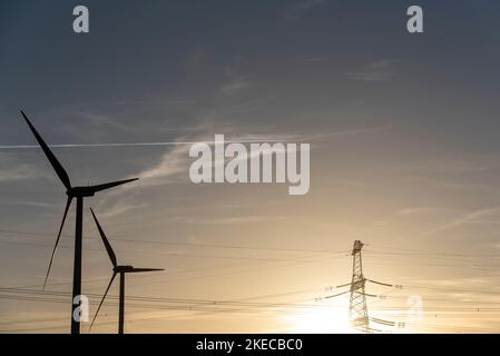 Deux éoliennes se tiennent à côté d'un poteau de puissance. Banque D'Images