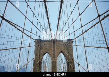 Photo en contre-plongée d'un drapeau américain volant sur le pont de Brooklyn, dans la ville de New York, aux États-Unis, sous un ciel bleu Banque D'Images