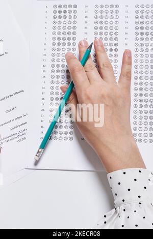 main d'une personne tenant un stylo et écrivant sur une feuille de papier qui a été imprimée avec des chiffres Banque D'Images