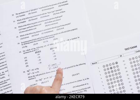 la main d'une personne qui pointe vers les numéros d'un morceau de papier imprimé pour utilisation Banque D'Images