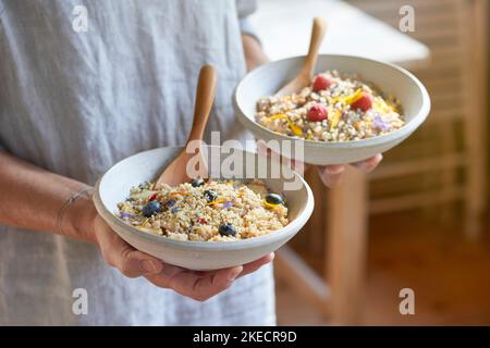 cuisine ayurvédique, femme tenant deux bols d'argile légère avec la semoule de porc et les fruits dans ses mains Banque D'Images