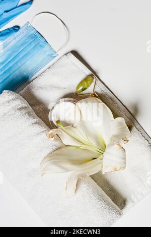 une fleur blanche sur une serviette avec un masque bleu sur la photo a été prise de dessus et n'est pas visible Banque D'Images