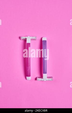 deux brosses à dents sur fond rose, l'une blanche et l'autre bleue avec une poignée violette Banque D'Images