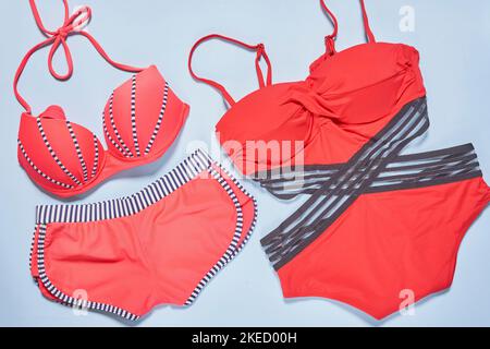 deux maillots de bain sur une surface blanche, l'un en rouge et l'autre en noir avec des bandes grises autour Banque D'Images