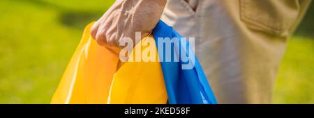 BANNER, LONG FORMAT Un homme tient un drapeau ukrainien entre ses mains. Concept patriote ukrainien, rassemblement en faveur de l'Ukraine Portrait d'une fille mécontente Banque D'Images