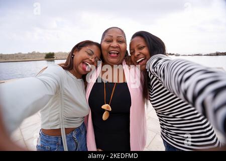 Heureux selfie de trois femmes latines regardant l'appareil-photo avoir du plaisir. Une femme d'âge moyen et deux jeunes. Banque D'Images